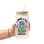 White mug featuring a colorful retro walking book character with flowers and a rainbow, “A Book A Day” lettering, “Read More Cry Less,” and “Keeps the Mental Breakdown Away” text.