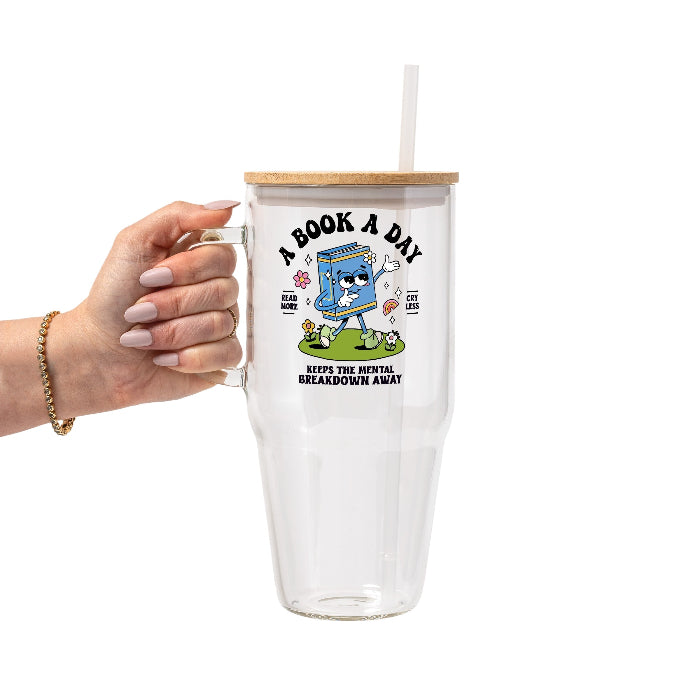 White mug featuring a colorful retro walking book character with flowers and a rainbow, “A Book A Day” lettering, “Read More Cry Less,” and “Keeps the Mental Breakdown Away” text.