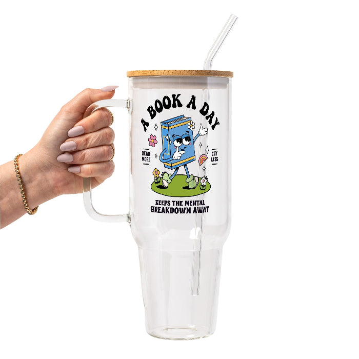 White mug featuring a colorful retro walking book character with flowers and a rainbow, “A Book A Day” lettering, “Read More Cry Less,” and “Keeps the Mental Breakdown Away” text.
