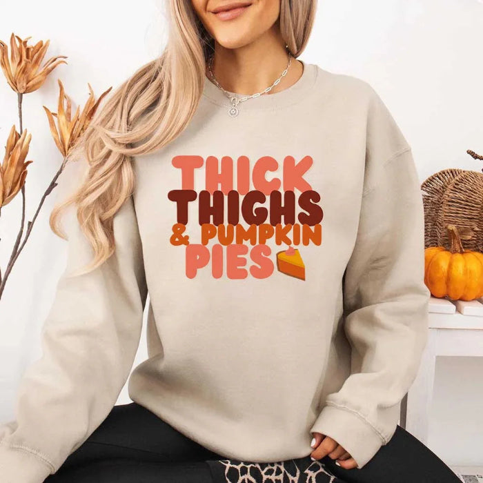 Thick Thighs and Pumpkin Pies fall sweatshirt featuring a funny Thanksgiving-inspired graphic on a cozy unisex crewneck in Sand