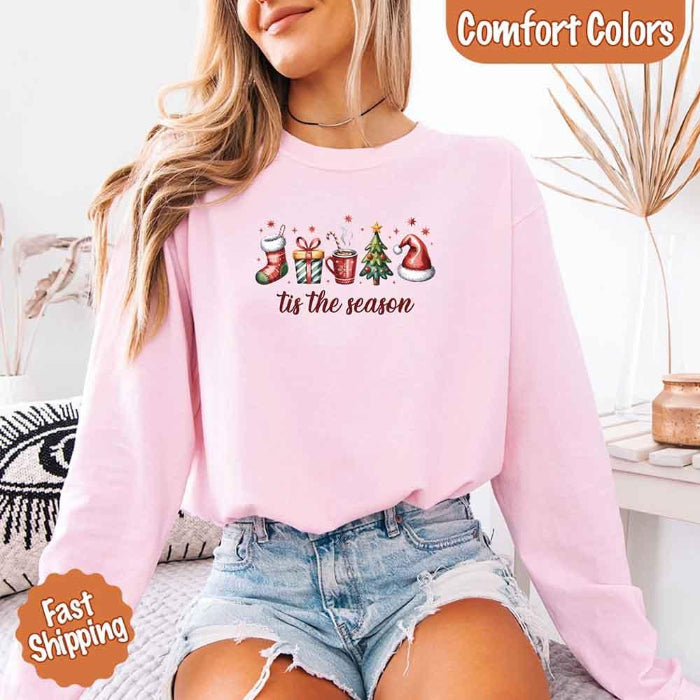 ’Tis The Season Comfort Colors long sleeve Christmas shirt featuring a festive holiday graphic on a soft garment-dyed 100% cotton tee in Light Pink