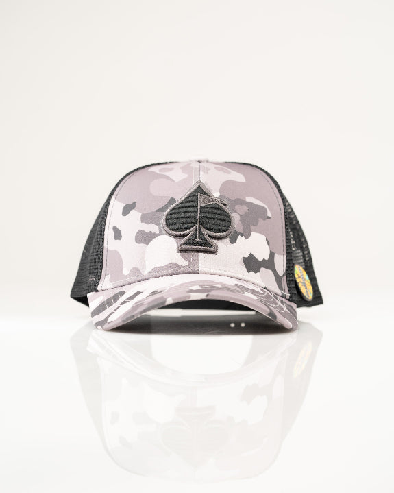 Urban Camo trucker golf hat by Pins & Aces featuring a gray, black, and white camouflage print, embroidered black spade logo, black mesh back, curved bill, and snapback design.
