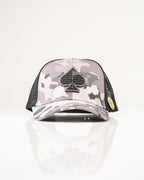 Urban Camo trucker golf hat by Pins & Aces featuring a gray, black, and white camouflage print, embroidered black spade logo, black mesh back, curved bill, and snapback design.