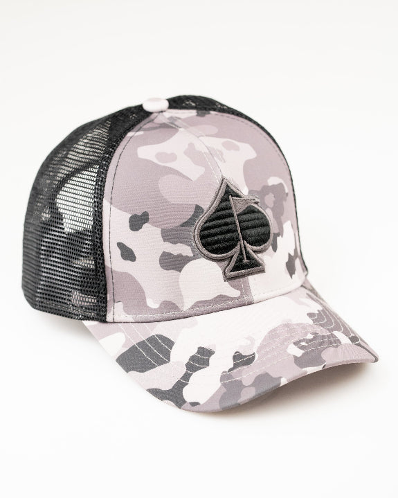 Urban Camo trucker golf hat by Pins & Aces featuring a gray, black, and white camouflage print, embroidered black spade logo, black mesh back, curved bill, and snapback design.