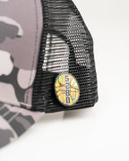Urban Camo trucker golf hat by Pins & Aces featuring a gray, black, and white camouflage print, embroidered black spade logo, black mesh back, curved bill, and snapback design.