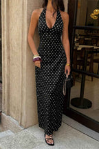 Women’s polka dot halter maxi dress featuring a sleeveless neckline, fitted bodycon silhouette, timeless polka dot print, and elegant long-length design in black.