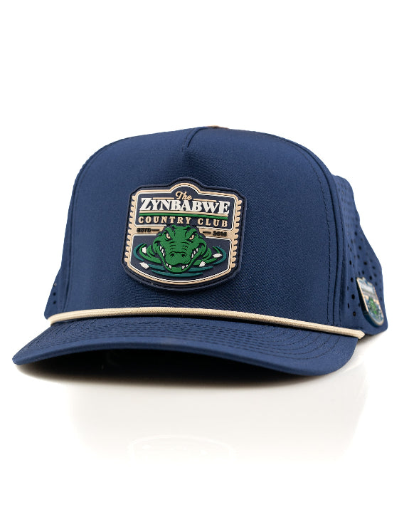 Zynbabwe Country Club Navy perforated rope golf hat by Pins & Aces with adjustable snapback, magnetic ball marker holder, and matching golf ball marker.