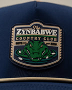 Zynbabwe Country Club Navy perforated rope golf hat by Pins & Aces with adjustable snapback, magnetic ball marker holder, and matching golf ball marker.