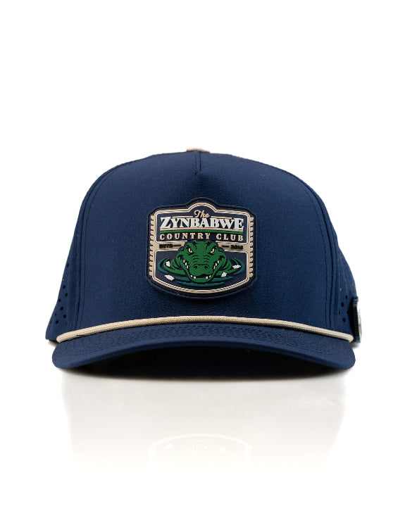 Zynbabwe Country Club Navy perforated rope golf hat by Pins & Aces with adjustable snapback, magnetic ball marker holder, and matching golf ball marker.