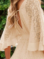 Hope Ruffle Hem Lace Mini Dress featuring delicate lace detailing, a flowy silhouette, feminine ruffle hem, and adjustable tie-back design, perfect for weddings, bridal showers, vacations, and spring or summer occasions. Color Cream